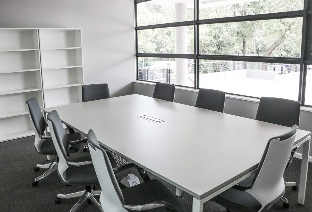 Boardroom with a white meeting table and grey high-back office chairs