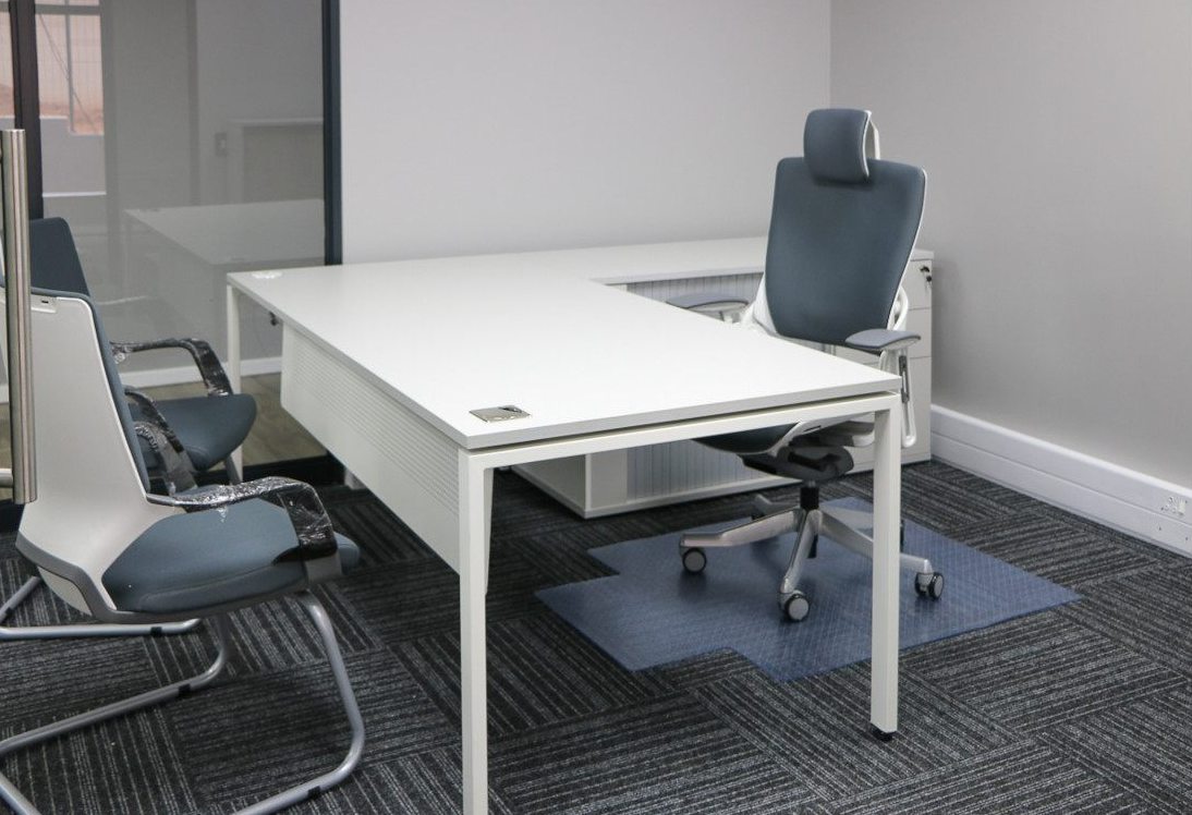 Private office with a white L-shaped desk, high-back chair and visitor chair