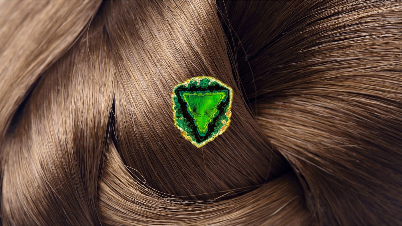 Tourmaline gem resting on glossy brown hair